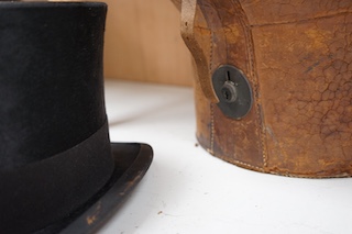 A gentleman’s black silk top hat with a black felt band and, cream silk lining, together with a brown leather case, hat height 17cm. Condition - silk brim worn in various places, leather case very poor